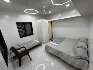 um quarto com uma cama e uma cadeira em Vatavriksha Guest House,Akkalkot em Akalkot