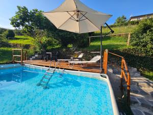 a large pool with an umbrella and a chair and a table at Soulhouse in Bieno