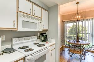 a kitchen with a white stove top oven next to a table at Lake Conroe Condo with Pool Access and Balcony! in Montgomery