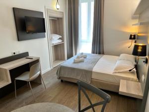 sypialnia z łóżkiem, biurkiem i telewizorem w obiekcie Hôtel du Nord w mieście Corte