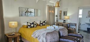 圣赫勒拿湾At3Brides Self Catering的卧室里有一张床、一把椅子和一面镜子