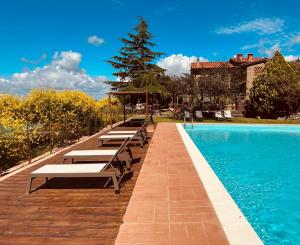 una fila de bancos sentados junto a una piscina en Borgo La Capraia, en Castelfranco di Sopra
