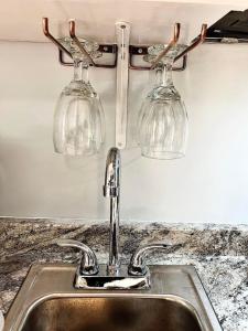 un lavello da cucina con due bicchieri da vino appesi a uno scaffale di Quality 4 Four. Pet Yes a Beaufort