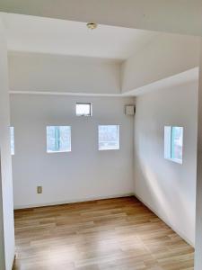 a white room with two windows and a wooden floor at Shinjuku Kabuki Youth Hostel#New Sunshine Room#50 second walk from Higashi Shinjuku subway#Automatic locking door at entrance in Tokyo