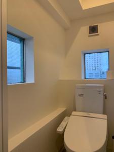 a bathroom with a white toilet and two windows at Shinjuku Kabuki Youth Hostel#New Sunshine Room#50 second walk from Higashi Shinjuku subway#Automatic locking door at entrance in Tokyo +18 photos