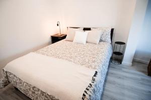 a bedroom with a bed with white sheets and pillows at Casa das Pôpas in A dos Cunhados