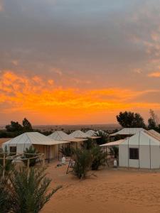 a group of tents in the desert at sunset at Desert Villa Boutique Hotel Merzouga in Merzouga