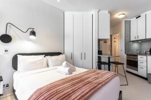a bedroom with a white bed and a kitchen at Flamingo 407 - Central Prime Sea Point Apartment in Cape Town