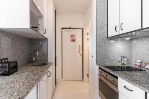 a kitchen with white cabinets and granite counter tops at Flamingo 407 - Central Prime Sea Point Apartment in Cape Town