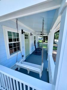 a porch with a swing on a blue house at Modern Cottage Downtown. Pet Yes in Beaufort