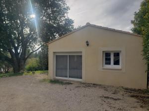 a small white house with a window in a yard at Maisonnette au cœur de Lauris in Lauris