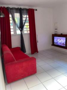 a living room with a red couch and a tv at Appartement Bella in Vieux Bourg