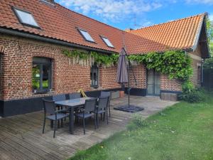 eine Holzterrasse mit einem Tisch, Stühlen und einem Sonnenschirm in der Unterkunft ferme de caractère avec piscine et cheminée in Sainghin-en-Mélantois
