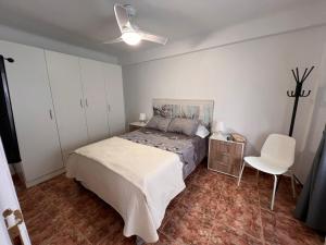 ein Schlafzimmer mit einem Bett und einem weißen Stuhl in der Unterkunft Apartamento en el centro de Nerja in Nerja