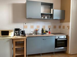 a small kitchen with white cabinets and a sink at Studio Soulac centre et plage in Soulac-sur-Mer