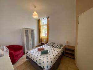 una camera da letto con un letto e una sedia rossa di Appartement familial centre et plage a Soulac-sur-Mer