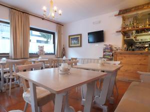 een eetkamer met tafels en stoelen en een tv bij Garnì Defrancesco in Campitello di Fassa