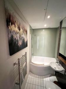 a bathroom with a sink and a tub and a toilet at Luxury studio with super fast WiFi gated development in London