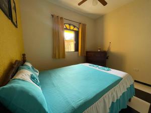 Schlafzimmer mit einem großen blauen Bett und einem Fenster in der Unterkunft Casa Pouso Aconchego Para Ti - pertinho de Trindade com conforto e churrasqueira in Paraty