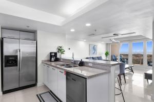 a white kitchen with a stainless steel refrigerator at Stunning Sunsets and SpaceX Views in South Padre Island