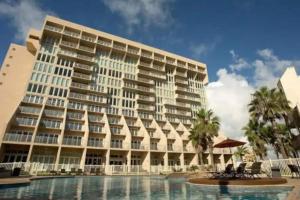 a large building with a pool in front of it at Stunning Sunsets and SpaceX Views in South Padre Island
