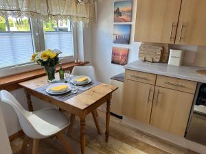 a small kitchen with a wooden table with flowers on it at Little Blue Cottage #9 in Fehmarn