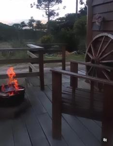 Un pozo de fuego junto a un banco y una rueda. en Gaia Cabanas - Urubici - Terra, en Mundo Novo