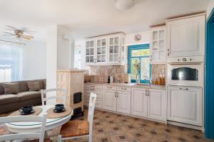 a kitchen with white cabinets and a table and a couch at Fészek Villa in Zalaegerszeg