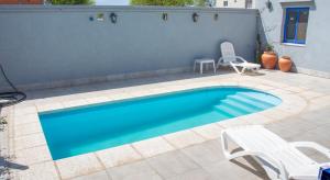 - une piscine avec 2 chaises et un banc dans l'établissement Departamentos La Justina, à Cafayate