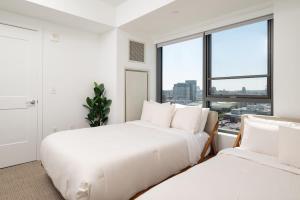 two beds in a white room with a window at Upscale 1BR near MIT Harvard with Parking in Cambridge