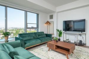 a living room with a green couch and a tv at Central Penthouse City Skyline Views Gym sleep 8 in Cambridge
