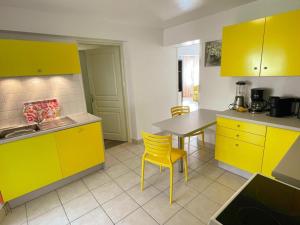 a kitchen with yellow cabinets and a table and chairs at Gîte familial spacieux près de Villandry, avec jardin, pétanque et WIFI - FR-1-381-595 in Lignières-de-Touraine +19 photos