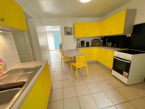 a kitchen with yellow cabinets and a table and chairs at Gîte familial spacieux près de Villandry, avec jardin, pétanque et WIFI - FR-1-381-595 in Lignières-de-Touraine