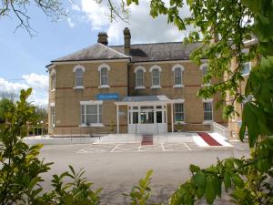 un gran edificio de ladrillo con un aparcamiento enfrente en Gatwick Cambridge Hotel, en Horley