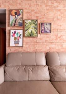 a couch against a brick wall with pictures on it at PALMAS EXPERIENCE - APARTAMENTO CONTEMPORÂNEO, vista serra, na quadra do shopping in Palmas