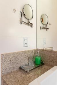 a bathroom counter with a green candle and two mirrors at PALMAS EXPERIENCE - APARTAMENTO CONTEMPORÂNEO, vista serra, na quadra do shopping in Palmas