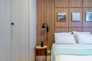 a bedroom with a bed and a table with a lamp at PALMAS EXPERIENCE - APARTAMENTO CONTEMPORÂNEO, vista serra, na quadra do shopping in Palmas