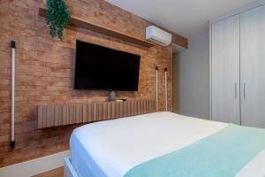 a bedroom with a brick wall with a tv on it at PALMAS EXPERIENCE - APARTAMENTO CONTEMPORÂNEO, vista serra, na quadra do shopping in Palmas