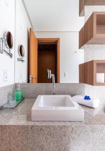 a bathroom counter with a white sink and a mirror at PALMAS EXPERIENCE - APARTAMENTO CONTEMPORÂNEO, vista serra, na quadra do shopping in Palmas