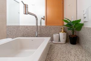 a bathroom with a white tub and a sink at PALMAS EXPERIENCE - APARTAMENTO CONTEMPORÂNEO, vista serra, na quadra do shopping in Palmas