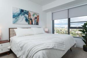 a white bedroom with a large bed and a window at Upscale Penthouse near MIT Harvard Central Square in Cambridge