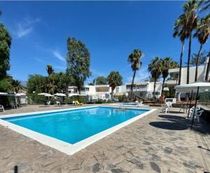 a swimming pool in a resort with palm trees at Buenas Flores Tenerife in Costa Del Silencio