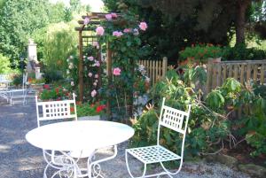 a table and chairs in a garden with flowers at Hostellerie de la Motte jean in Saint-Coulomb