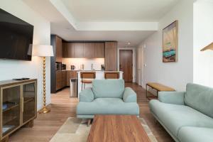 a living room with a blue couch and a kitchen at Luxury Apartment w King Bed Shared Pool & Rooftop in Cambridge