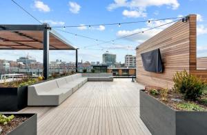 a rooftop patio with couches and a tv on a building at Luxury Apartment w King Bed Shared Pool & Rooftop in Cambridge