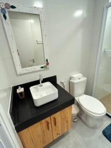 a bathroom with a sink and a toilet and a mirror at Melhores Flats - Espaçoso, pertinho do mar in João Pessoa