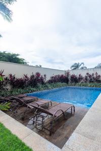 a swimming pool with two chairs and a table at PALMAS EXPERIENCE - APARTAMENTO CONTEMPORÂNEO, vista serra, na quadra do shopping in Palmas