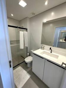 a bathroom with a sink and a toilet and a mirror at Apto Elegante com Localização Privilegiada e Rooftop incrível in Florianópolis