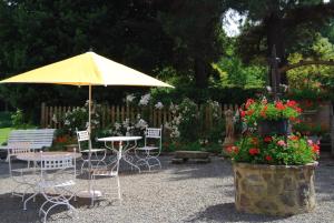 a table and chairs with an umbrella and flowers at Hostellerie de la Motte jean in Saint-Coulomb
