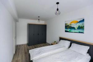 a bedroom with a white bed and a black door at Dominic Junior Apartment Sighisoara in Sighişoara